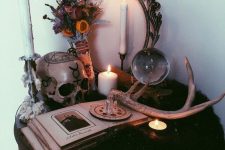 13 a boho Halloween table with dried blooms, antlers, candles, a vintage photo album and a painted skull