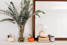 13 a very simple fall arrangement of some natural pumpkins, a candle and eucalyptus in a clear vase