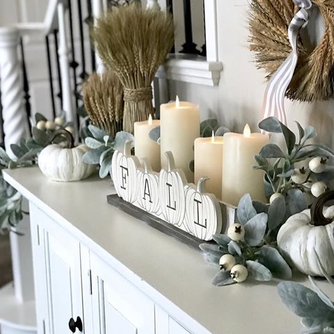 an arrangement of candles in a box with pumpkin decor, pale greenery and berries plus wheat bundles is very stylish