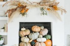 14 modern fall decor with natural pumpkins stacked in front of the built-in fireplace and a dried wall hanging over them