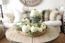 14 neutral fall decor of a basket tray with greenery, white pumpkins and some more pumpkins in crates under the table