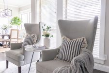 18 dove grey wingback chairs with decorative nails, blankets and pillows for a cozy nook in your space