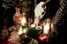 19 boho witch Halloween styling with green leaves, an animal skull, feathers, crystals, candles and faux fur