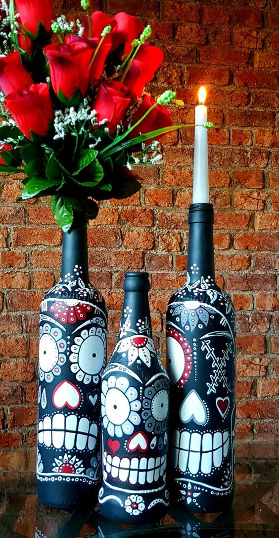 bottles painted with Mexican Day of the Dead sugar skulls can be used as candleholders or vases for blooms