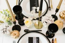 22 a refined modern fall tablescape with black plates, glasses, gold and black candles and cutlery plus blooms and pumpkins