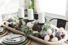 24 a stylish neutral fall tablescape with a wooden tray with candles, mini pumpkins, pinecones, greenery and berries, green and white plates and woven placemats