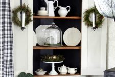 25 a stylish white corner storage unit with black inner, wreaths and decor for Christmas