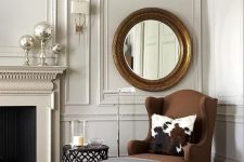 25 a very refined neutral living room with a brown wingback lounger, a refined round mirror and lots of molding on the walls