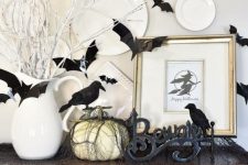 a Halloween console with a pumpkin, letters, blackbirds, and plates on the wall is very contrasting and bold