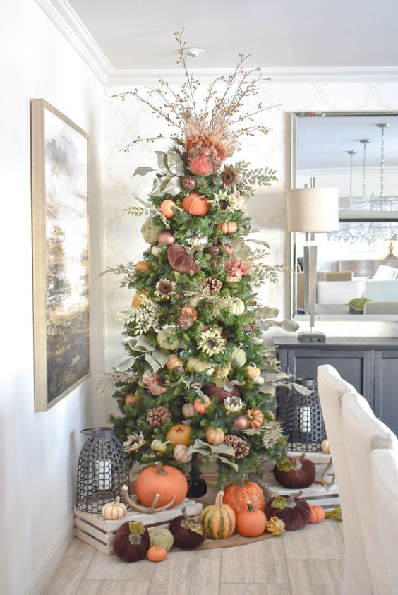 a Thanksgiving tree with faux and velvet pumpkins, pinecones, foliage, greenery and branches with berries plus more pumpkins under it