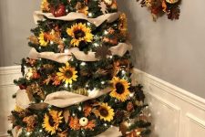a Thanksgiving tree with tan ribbons, lights, sunflowers, leaves and pumpkins topped with a sunflower