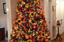 a bright fall tree with lights, plaid ribbons, faux pumpkins, pears, sunflowers and a red bow on the top
