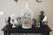 a contrasting Halloween console with cages, candleholders, a skeleton, some birds and animal skeletons