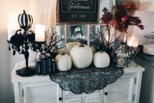 a farmhouse console with white pumpkins, black lace, a black candelabra, candles and a chic sign for Halloween