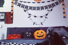 a fun and whimsy Halloween bedroom with bat and pumpkin garlands, lights, a black bed with fun pillows and plushies
