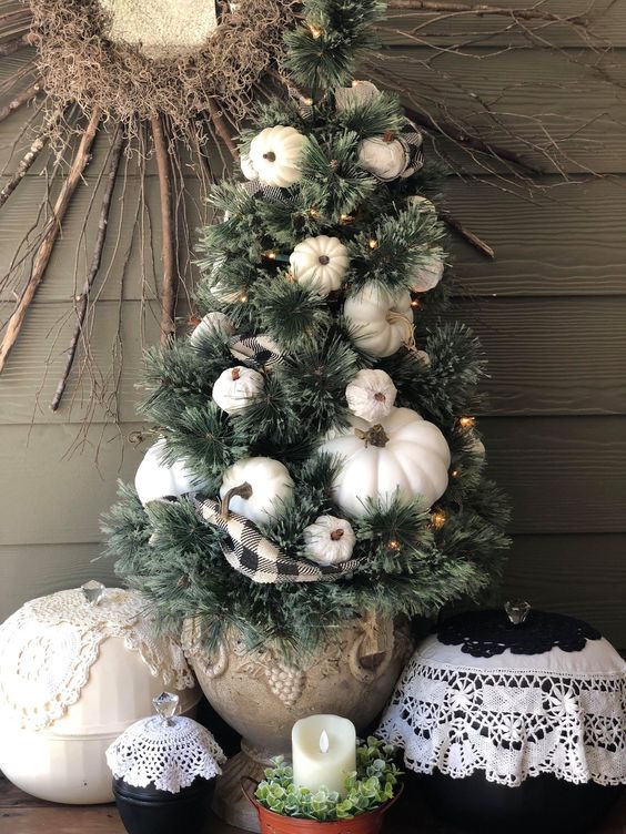 a mini fall tree with white pumpkins, lights and a plaid ribbon is a stylish decoration for fall or Thanksgiving