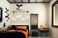 a minimalist Halloween bedroom with black bat stickers, black and orange bedding and a matching cabinet plus a jack-o-lantern