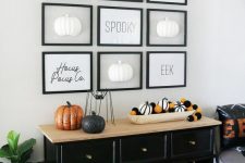 a minimalist Halloween gallery wall with letters and half pumpkins in black frames