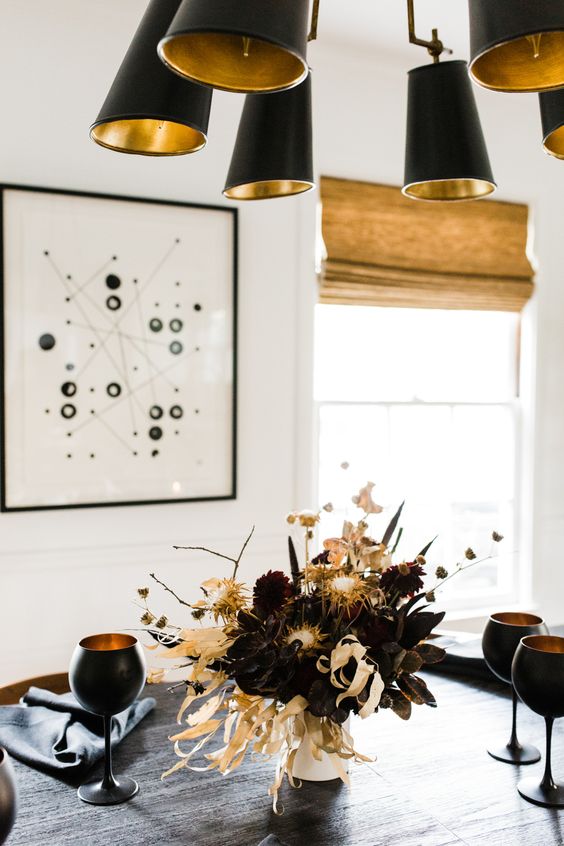 a moody floral arrangement with deep purple and brugundy blooms, branches, dried flowers and corn husks