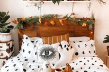 a natural Halloween bedroom with a fern and leaf garland, lights, leaves, spooky bedding and pillows, ghosts and pumpkins