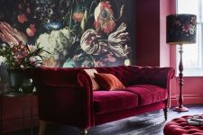 a refined living room with a floral statement wall, a burgundy velvet Chesterfield sofa and a matching ottoman, a floral floor lamp