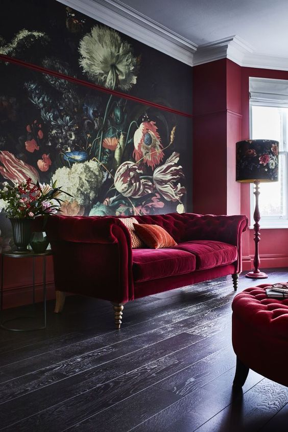 a refined living room with a floral statement wall, a burgundy velvet Chesterfield sofa and a matching ottoman, a floral floor lamp