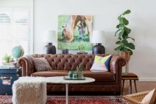 a relaxed living room with a brown leather Chesterfield sofa, a woven chair, a fur stool and some plants