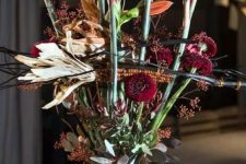 a scary Halloween floral arrangement with orange and burgundy blooms and greenery plus corn cobs