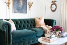 a sophisticated living room with a teal velvet Chesterfield sofa, gold candelabras and a table plus a bold artwork