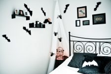 a stylish black and white Halloween bedroom spruced up with bats, spiders, a light cage and soem artworks on the wall