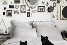 a stylish black and white bedroom with a bold and catchy gallery wall, signs and two black cats is Halloween-ready