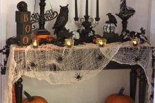 a vintage Halloween console with black candles, black birds, a spooky tree, some letters and spiderweb with spiders