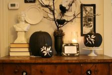 a vintage-inspired display with black and white pumpkins, buntings and blackbirds on branches