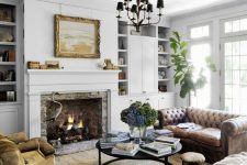 a welcoming and chic living room with a brown leather Chesterfield sofa, a neutral one, tan velvet chairs and a real working fireplace