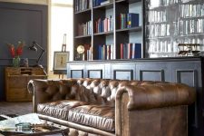 an elegant moody home office with a brown leather Chesterfield sofa that is a centerpiece here