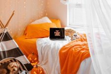 carved pumpkin lanterns, a black and white teepee for the dog, bright orange bedding and lights