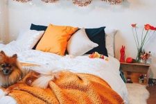 chic and easy Halloween bedroom decor with orange and black pillows, an orange blanket, brigth letters, pumpkins and letters