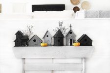 minimalist Halloween decor with grey and black birdhouses, mini pumpkins and larger ones on the floor