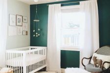 02 a beautiful nursery with a jute rug, a cool bulb chandelier, a rattan chair and an emerald statement wall