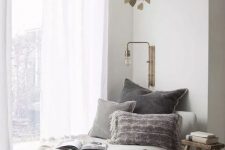 04 a grey lounger with pillows and blankets, a stylish wall sconce and a wooden stool are nice for decorating a reading nook
