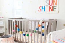 11 a colorful gender neutral nursery with grey and white furniture, colorful letters and garlands, printed textiles and a polka dot wall