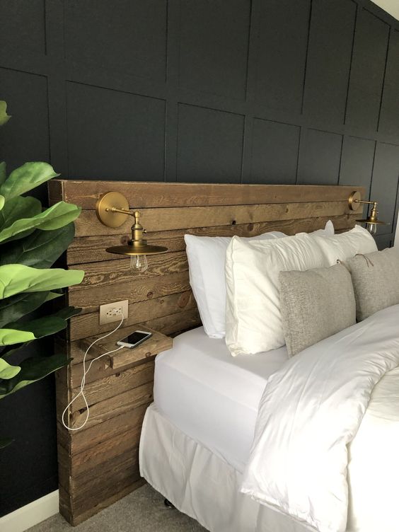 a modern to boho bedroom with a reclaimed wooden headboard, brass sconces and a statement plant