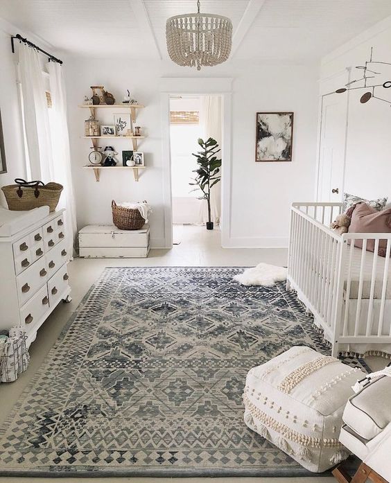 a neutral famrhouse meets boho nursery with a beaded chandelier, a Moroccan blanket ottoman and baskets