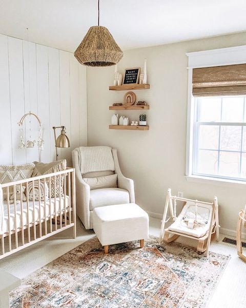 a farmhouse neutral nursery with light colored furniture, a boho rug, a woven lamp and wooden furniture