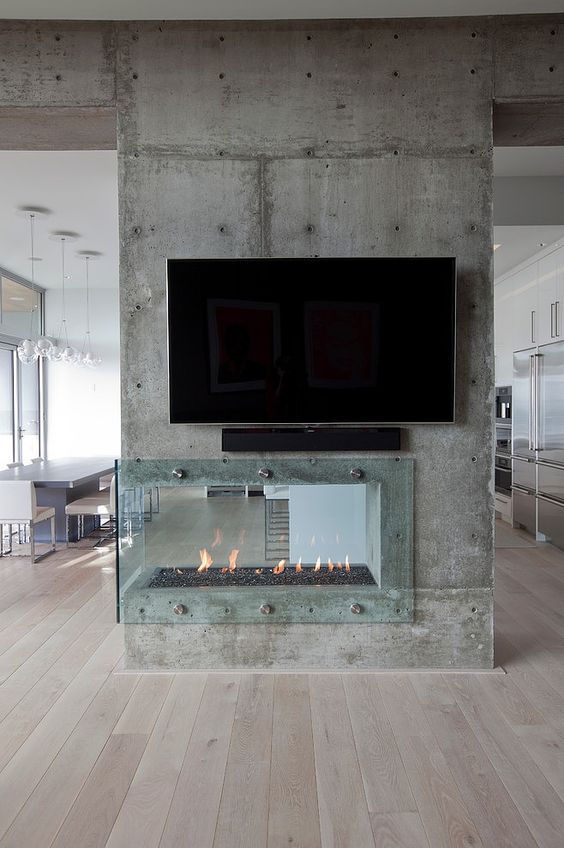 a contemporary built in fireplace built into a raw concrete wall, with a glass cover looks rough and very catchy