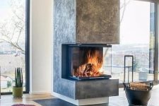 a contemporary fireplace with a glass cover, some firewood in a leather basket and soem faux fur