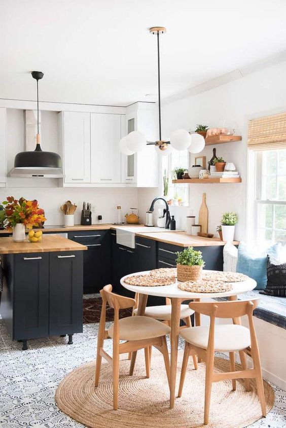 a contemporary kitchen with black and white cabinets, wooden countertops, mid century modern lamps and a dining zone with a round table and chairs