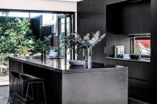 a contemporary moody kitchen with sleek black cabinetry, a kitchen island, a glazed wall with an entrance to a courtyard