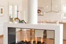 a contemporary white fireplace with a glass cover, an enthanol fireplace with faux firewood is a very cozy piece to rock