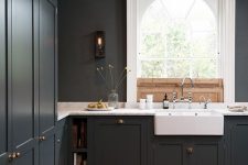 a dark and moody kitchen with graphite grey cabinetry, white marble countertops, a pendant lamp is very elegant and simple